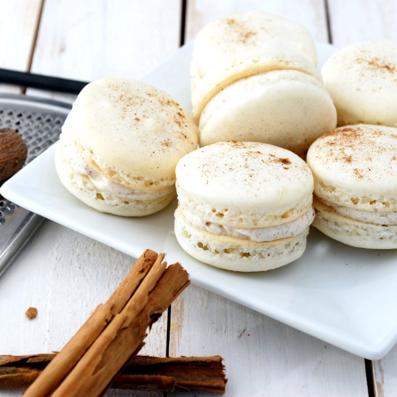 Eggnog Macarons, a classic almond macaron filled with cinnamon and nutmeg spiced buttercream - tastes just like eggnog! Visit http://www.cakeandallie.com for the recipe